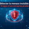 Illustration professionnelle de cybersécurité sur fond bleu technologique avec des réseaux de données. Au centre, un bouclier numérique rouge brillant avec un point d'exclamation, entouré d'une interface de données circulaire. En haut, le titre en français : « Détecter la menace invisible : 10 signes d'une entreprise piratée »